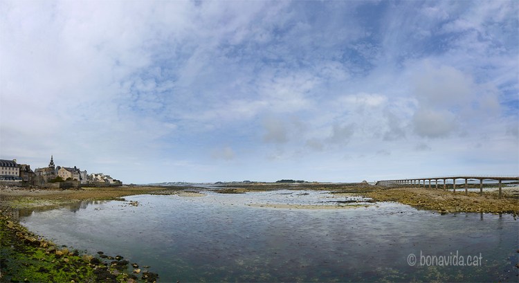 Roscoff a l'esquerra, davant l'illa de Batz, i a la dreta el llarg pont per arribar al ferri si la marea és baixa
