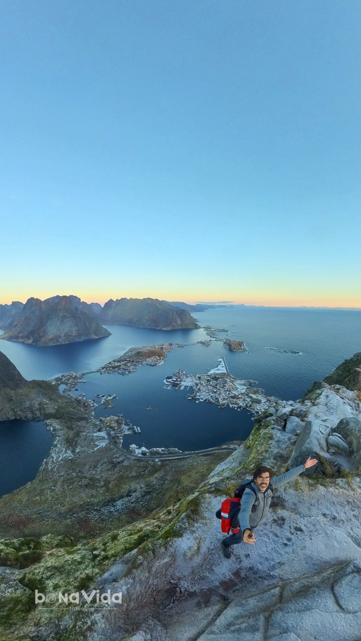 Vista panoràmica de la costa amb un home a la vora d'un penya-segat, amb un mar tranquil i illes a l'horitzó.