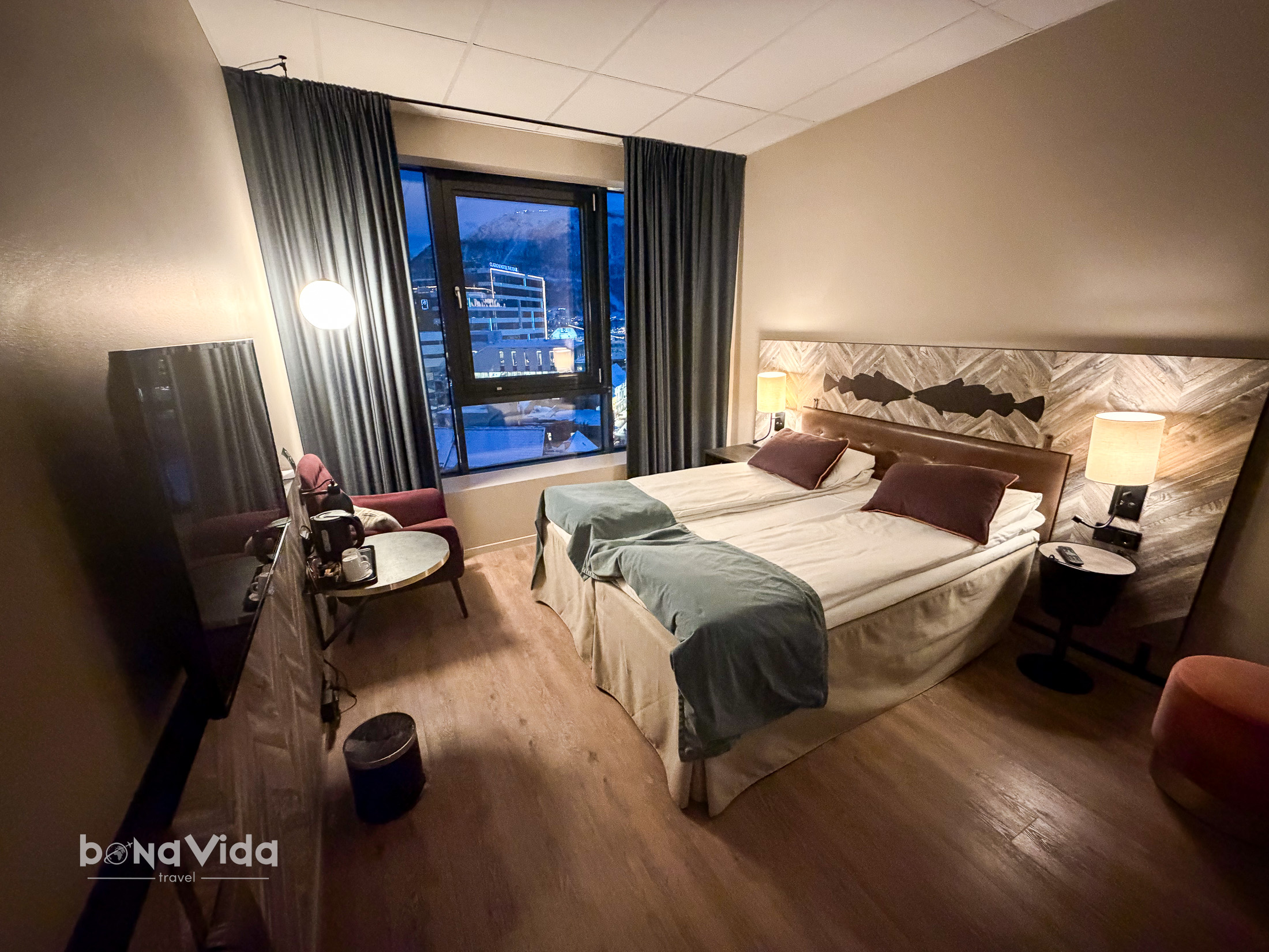 Habitació d'hotel moderna amb dues llits, decoració elegant, finestra amb vista exterior i escriptori. Il·luminació càlida i mobles funcionals.